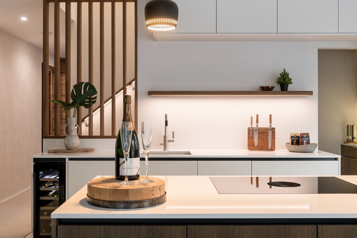 In an open-plan kitchen, LED strip lighting under the open shelf illuminates the worktop